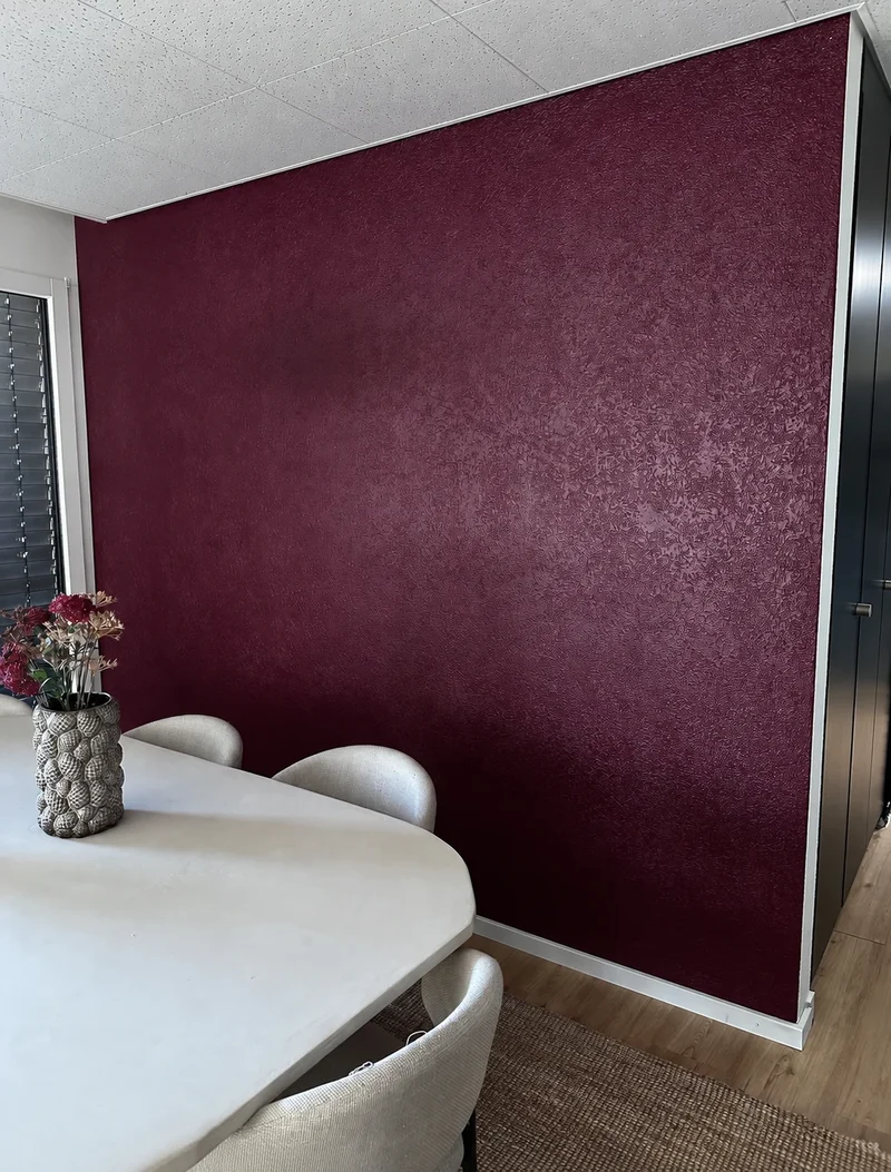 Mur bordeaux texturé dans une salle à manger, avec table et chaises claires
