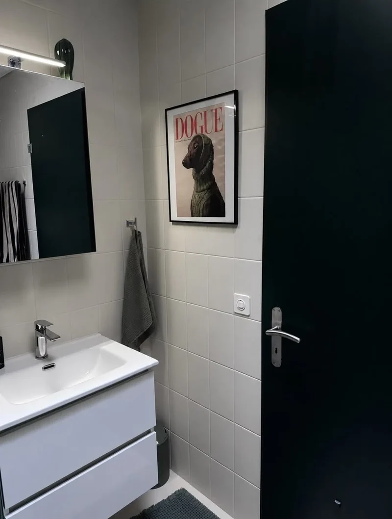 Porte vert sombre à côté d’une vasque et de murs blancs dans une salle de bains