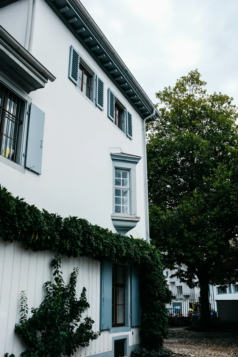 Façade blanche et volets bleu-gris entourés de végétation